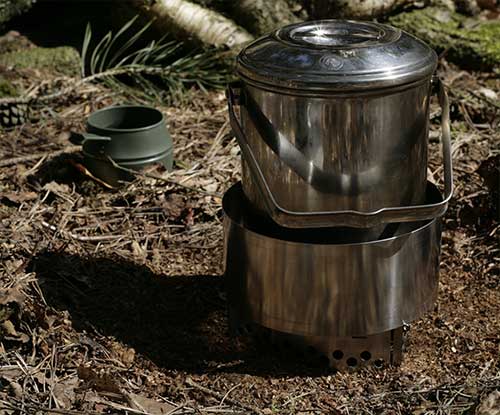 A billy can on a small alchohol stove with windshield