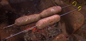 Sausages grilled over a bed of embers. If you are cooking food that needs to be done right through you don't want lots of flame.
